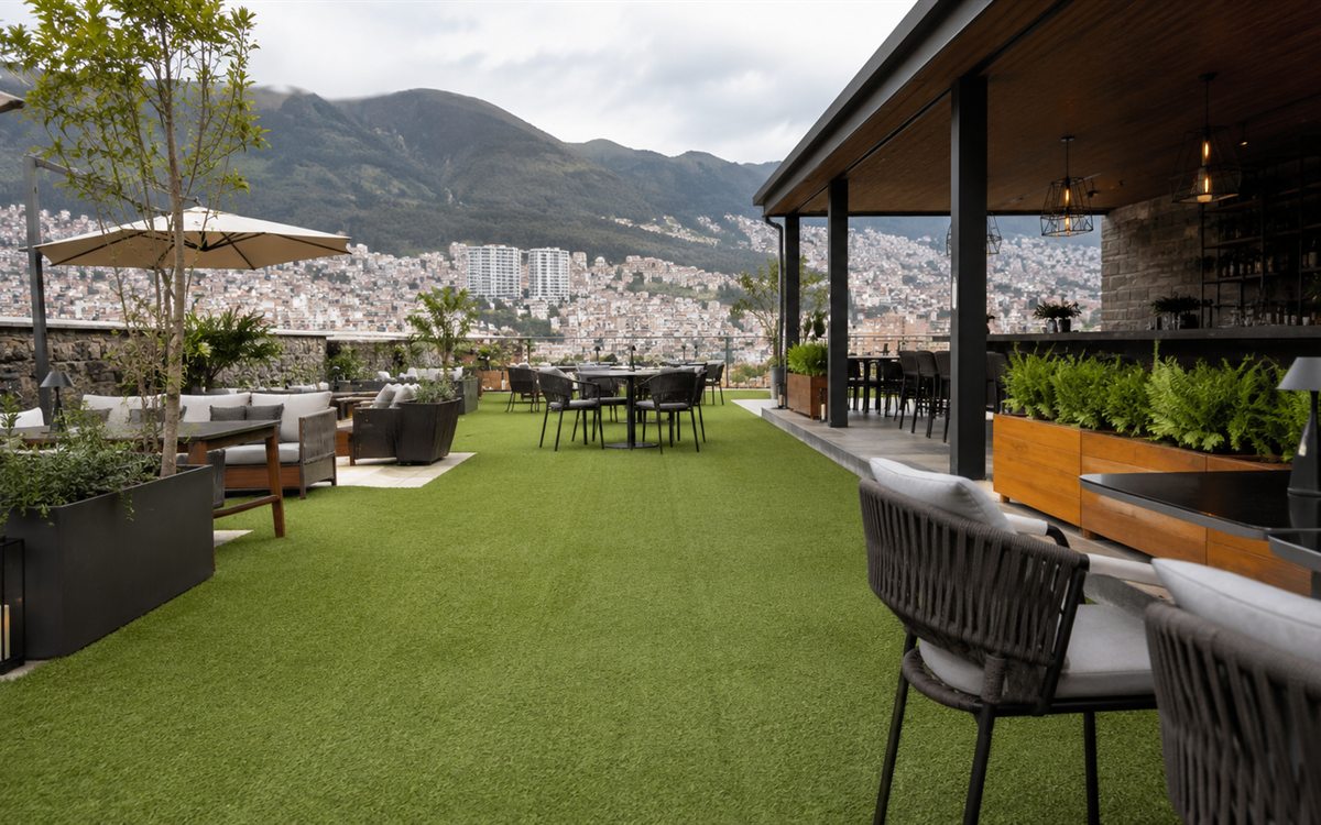 Terraza de restaurante con césped sintético y vista de Quito